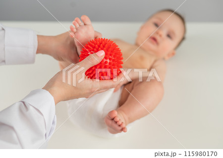 A doctor massages a baby's foot using a spiked ball. 115980170