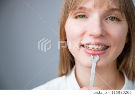 The woman jokingly tightens the wire of the brakes with a wrench. Bite correction device 115980260