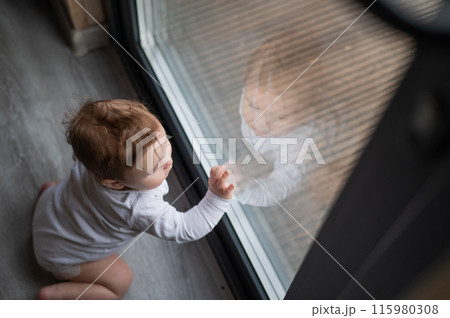 Baby boy standing by the patio window. Baby boy standing by the patio window. 115980308