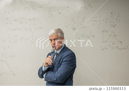 Mature man stands at a white board with written formulas. Mature man stands at a white board with written formulas. 115980313