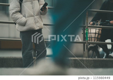 都会の街角に立つスマホを操作する若い男性 115980449