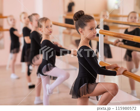 Cute little girls in black swimsuits and tutu do ballet at the barre. Cute little girls in black swimsuits and tutu do ballet at the barre. 115980572