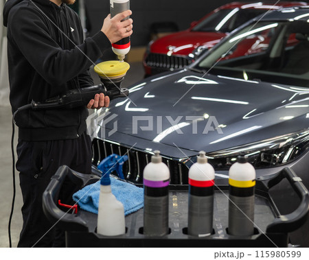 The master applies a special composition to the device for polishing the surface of the car body. The master applies a special composition to the device for polishing the surface of the car body. 115980599
