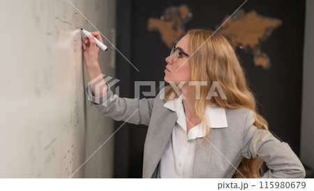 Young woman scientist writes formulas on a white board.  115980679