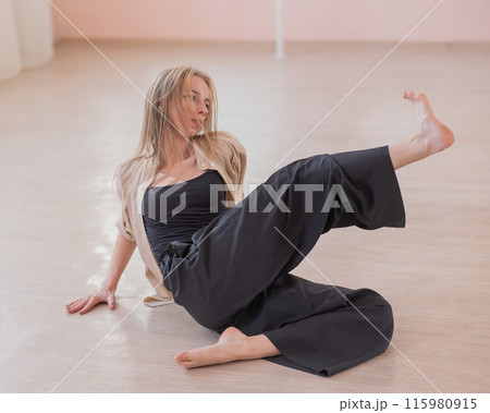 Caucasian woman dancing contemporary on the floor in a ballet class. Caucasian woman dancing contemporary on the floor in a ballet class. 115980915