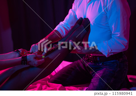 A man holds a woman by the ankles. BDSM concept. 115980941