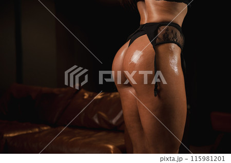 Close-up of a woman's tanned athletic buttocks oiled up.  115981201
