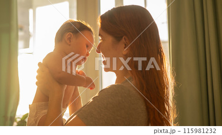 Caucasian woman gently lifts up her newborn son.  115981232