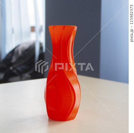 Object in the form of a vase of red color printed on a 3D printer. Three-dimensional model printed on a 3D printer from molten plastic of red color. Concept 3D Printing. FDM 3D Printing technology 115982373