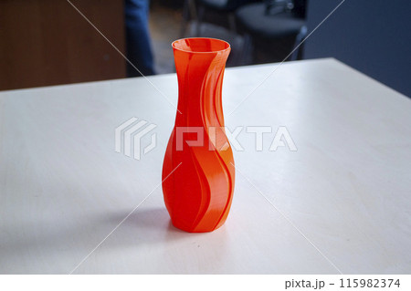Object in the form of a vase of red color printed on a 3D printer. Three-dimensional model printed on a 3D printer from molten plastic of red color. Concept 3D Printing. FDM 3D Printing technology 115982374