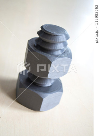 Object in form of washer and bolt of gray color printed on 3D printer. Three-dimensional model printed on 3D printer from molten plastic of red color. Concept 3D Printing. FDM 3D Printing technology Object in form of washer and bolt of gray color printed on 3D printer. Three-dimensional model printed on 3D printer from molten plastic of red color. Concept 3D Printing. FDM 3D Printing technology 115982562