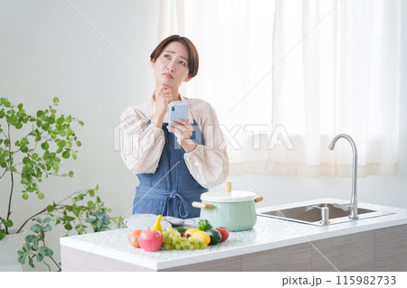 スマホで料理のレシピを調べる女性（キッチン・主婦） 115982733