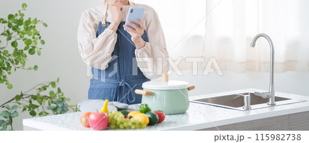 スマホで料理のレシピを調べる女性（キッチン・主婦） 115982738