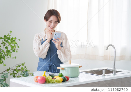 スマホで料理のレシピを調べる女性（キッチン・主婦） 115982740