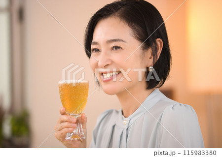 美味しそうにビールを飲むミドル女性 115983380