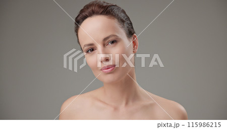 Beauty, health, cosmetics, anti-aging therapy and skin care concept - young beautiful brunette Caucasian woman touching face and looking at camera Beauty, health, cosmetics, anti-aging therapy and skin care concept - young beautiful brunette Caucasian woman touching face and looking at camera 115986215