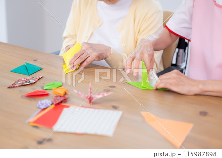 介護イメージ 折り紙を折るシニア女性と介護士 介護イメージ 折り紙を折るシニア女性と介護士 115987898