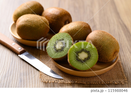 Green kiwi fruit on wooden bowl with kitchen knife, Healthy eating 115988046