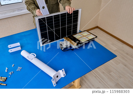 Eco-friendly street lamp with solar panel and LED lantern, woman mounts parts on bracket holder. Eco-friendly street lamp with solar panel and LED lantern, woman mounts parts on bracket holder. 115988303