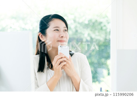 職場でスマートフォンを手に持つ若い女性 115990206