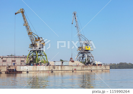 Yellow green portal cranes stand on a quay in harbor Yellow green portal cranes stand on a quay in harbor 115990264