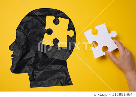 Silhouette of a human head holding a puzzle piece on a yellow background, representing mental health Silhouette of a human head holding a puzzle piece on a yellow background, representing mental health 115991464