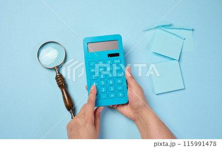Magnifier and calculator on a blue background, budget calculation. 115991478