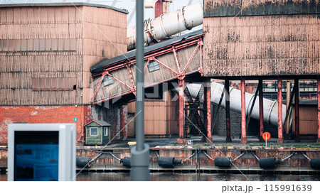 A large industrial building with a red roof and a white pipe 115991639