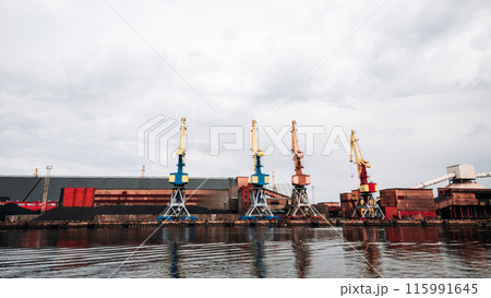 A large industrial area with a lot of cranes and a large body of water 115991645