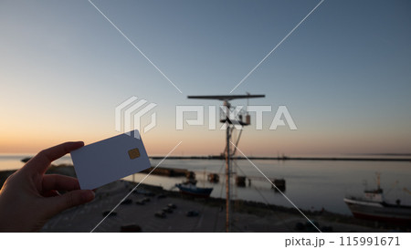 A person holding a credit card in front of a boat A person holding a credit card in front of a boat 115991671