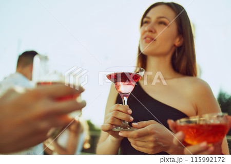 Celebratory vibes fill air as friends clink their glasses, savoring warmth and each other's company. Party outdoor. Celebratory vibes fill air as friends clink their glasses, savoring warmth and each other's company. Party outdoor. 115992172