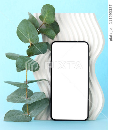 Smart Phone with blank screen stands in front a white decor wave and eucalyptus plant, on turquoise background Smart Phone with blank screen stands in front a white decor wave and eucalyptus plant, on turquoise background 115993327