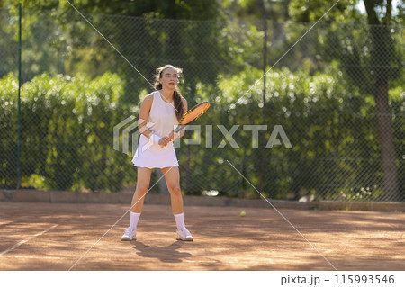 A woman is playing tennis on a court 115993546