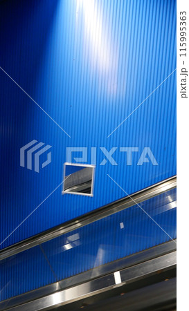 青い壁とエスカレーターが特徴のモダンな風景 115995363