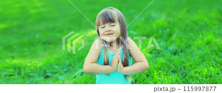 Happy little girl child standing on the grass in summer green park 115997877