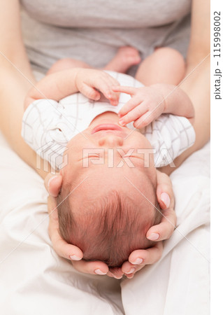 Mother Cradling Crying Newborn in Her Arms 115998002