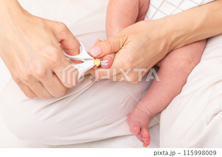 Mother cuts toenails of newborn 115998009