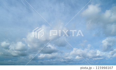 Dramatic moving white cumulus and cirrocumulus clouds or puffy fluffy cloudscape on beautiful sunny blue sky. Timelapse. 115998107