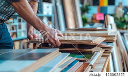 A man is browsing wood flooring samples at a home improvement store 116002375