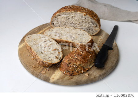 Round freshly oat baked bread sliced on a cutting board.  116002876