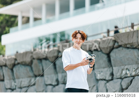 屋外でドローンを使った撮影を行う映像クリエイター 116005018