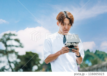 屋外でドローンを使った撮影を行う映像クリエイター 116005023