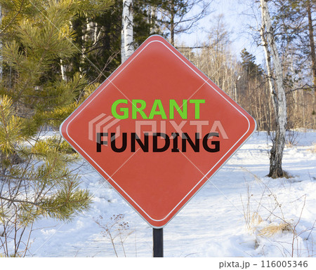 Grant funding symbol. Concept words Grant funding on beautiful red road sign. Beautiful forest snow blue sky background. Business and grant funding concept. Copy space. Grant funding symbol. Concept words Grant funding on beautiful red road sign. Beautiful forest snow blue sky background. Business and grant funding concept. Copy space. 116005346