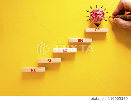 Resilience symbol. Concept word Resilience on beautiful wooden blocks. Light bulb icon. Businessman hand with pen. Beautiful yellow background. Business resilience concept. Copy space. 116005389