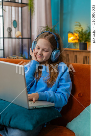 Preteen child girl in headphones using laptop listens to music or lesson distance online learning Preteen child girl in headphones using laptop listens to music or lesson distance online learning 116006038