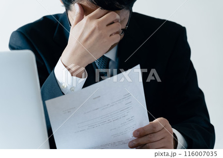 書類を見て悩む採用担当の男性 116007035