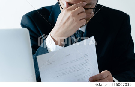 書類を見て悩む採用担当の男性 116007039