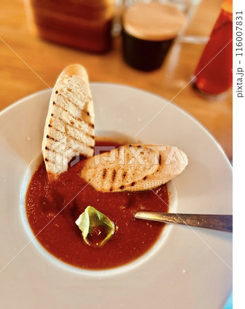 Gazpacho soup with toasted bread on a white plate in a restaurant Gazpacho soup with toasted bread on a white plate in a restaurant 116007831