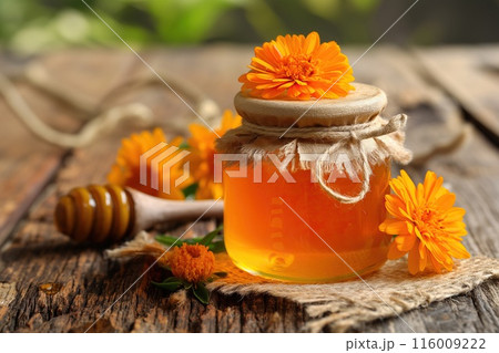 Jar of honey with calendula flowers on wooden table, closeup 116009222