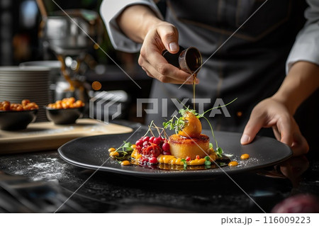 Chef decorating appetizer with fruits and berries on black plate 116009223